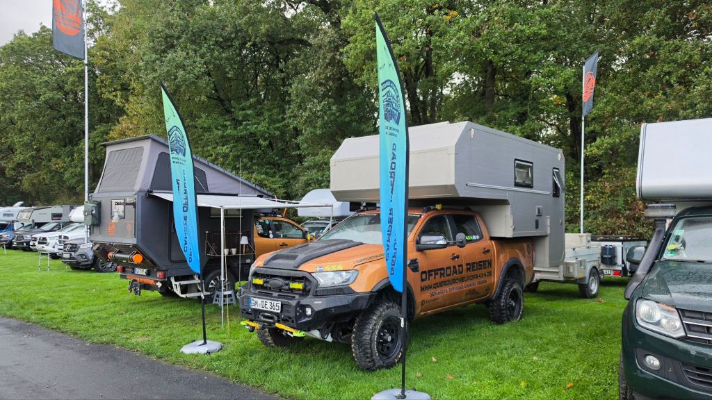 Eine Ausstellung von Offroad-Fahrzeugen und Campern auf einer grünen Wiese, mit mehreren Unternehmen, die ihre Produkte präsentieren.